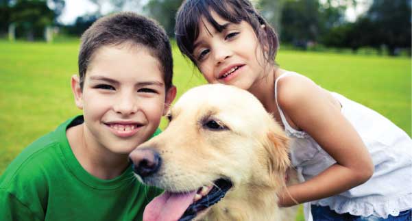 Children playing with a dog on a healthy lawn